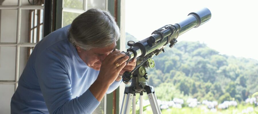 Mann beobachtet durch ein Fernrohr im Garten