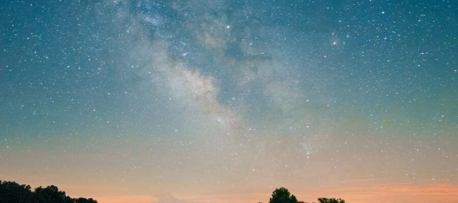 Milchstraße über einer Landschaft bei Nacht, leuchtender Sternenhimmel